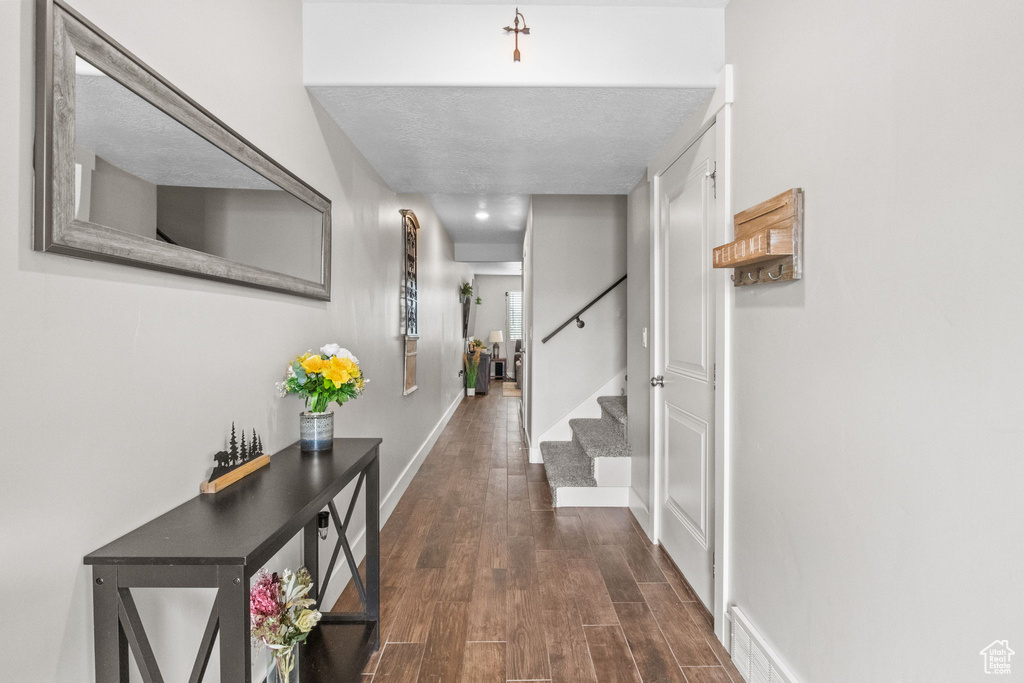 Corridor with dark wood finished floors, stairway, and baseboards