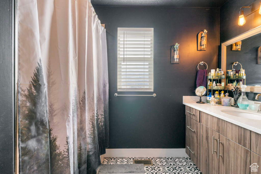 Bathroom with tile patterned flooring, visible vents, vanity, and baseboards