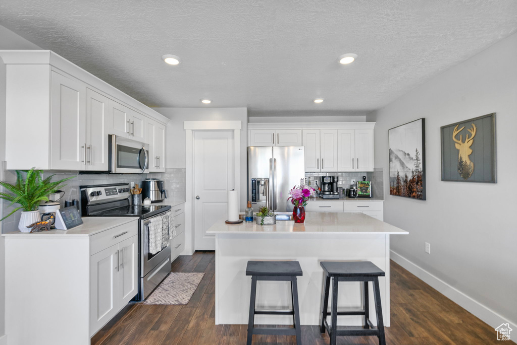 Kitchen featuring stainless steel appliances, light countertops, white cabinetry, and a kitchen island