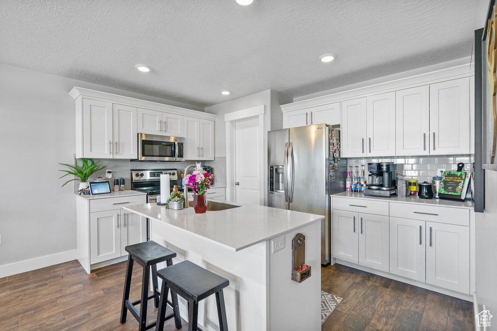 Kitchen featuring white cabinetry, stainless steel appliances, light countertops, and a center island