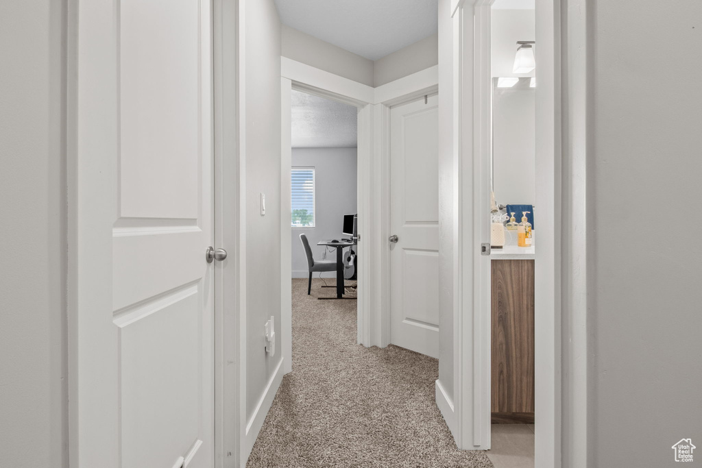 Hall with a desk, light carpet, and baseboards