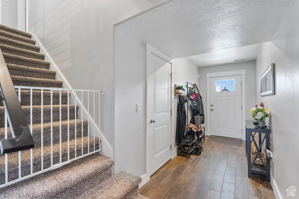 Entrance foyer with visible vents, stairway, a textured ceiling, wood finished floors, and baseboards