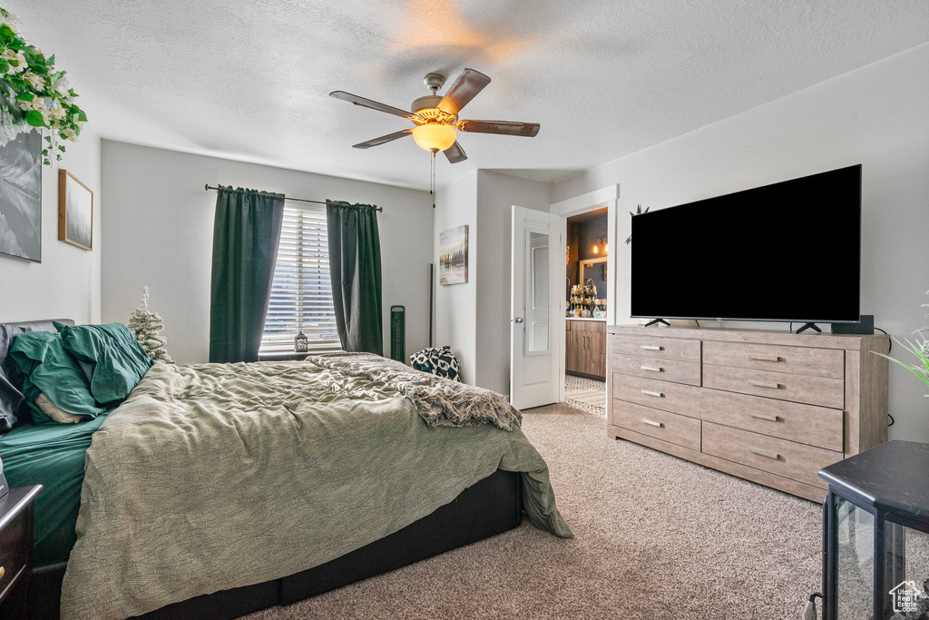 Carpeted bedroom featuring a ceiling fan and a textured ceiling