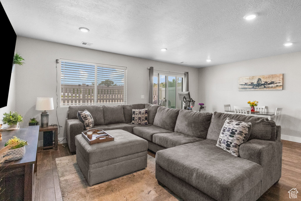 Living room with a textured ceiling, wood finished floors, and recessed lighting