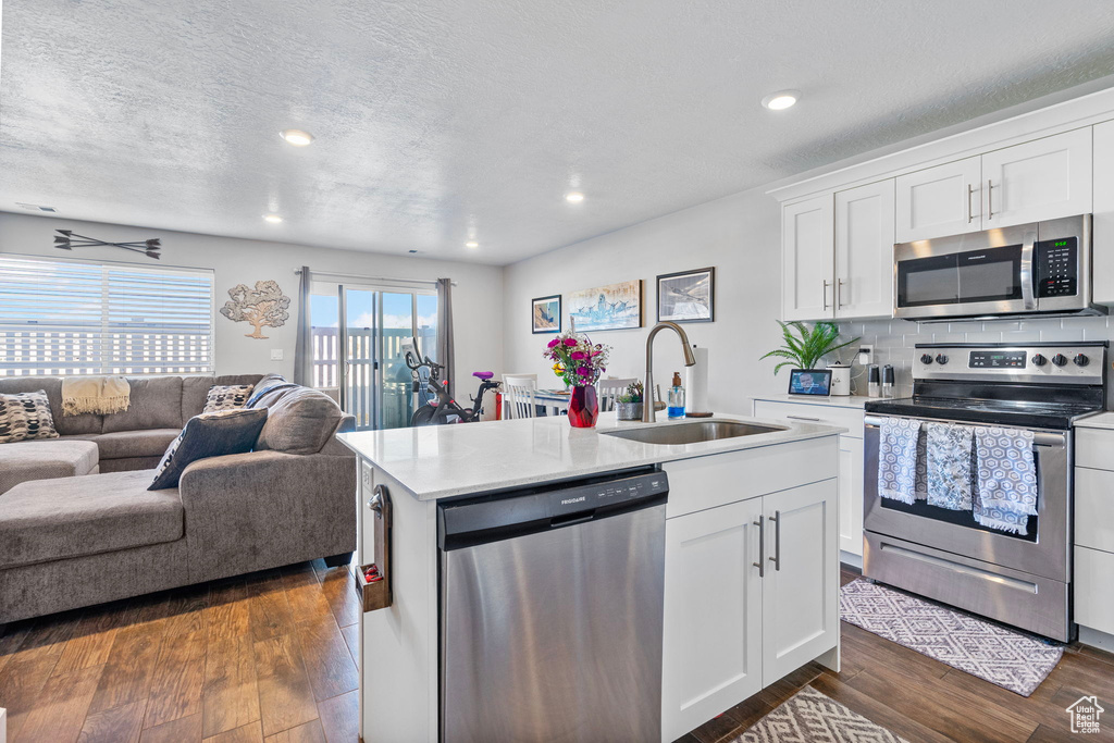 Kitchen with stainless steel appliances, a sink, light countertops, and white cabinets