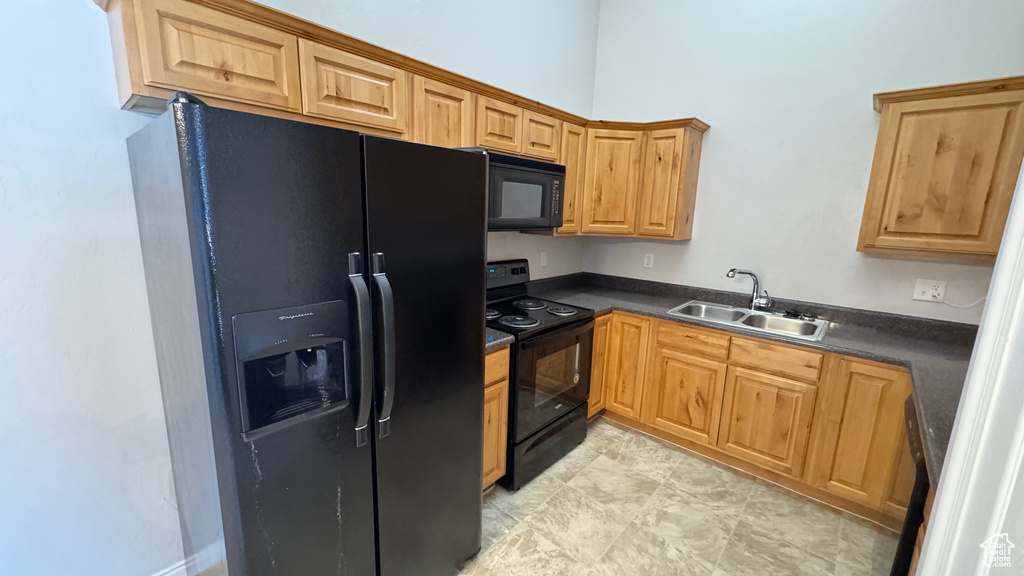 Kitchen featuring black appliances, a sink, and dark countertops