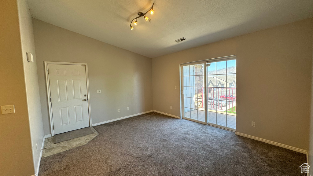 Empty room with lofted ceiling, dark colored carpet, and baseboards