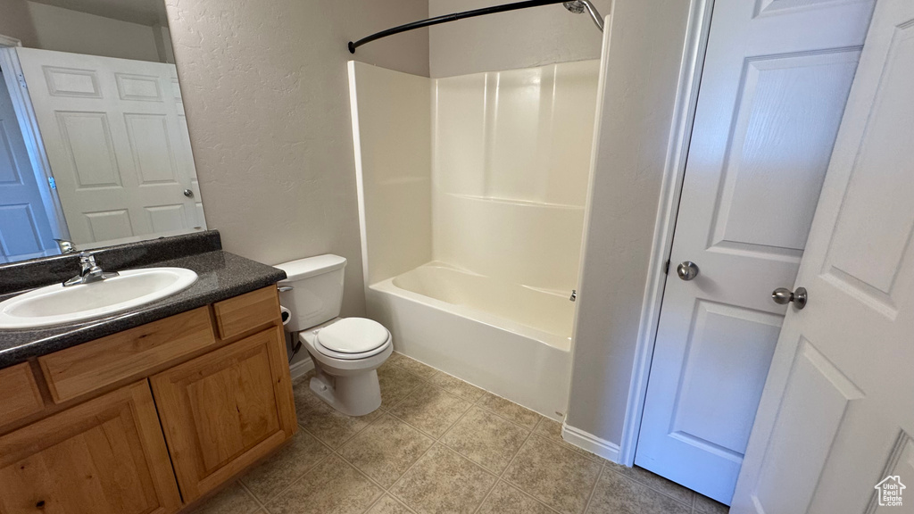Bathroom with a textured wall, toilet, vanity, and tub / shower combination