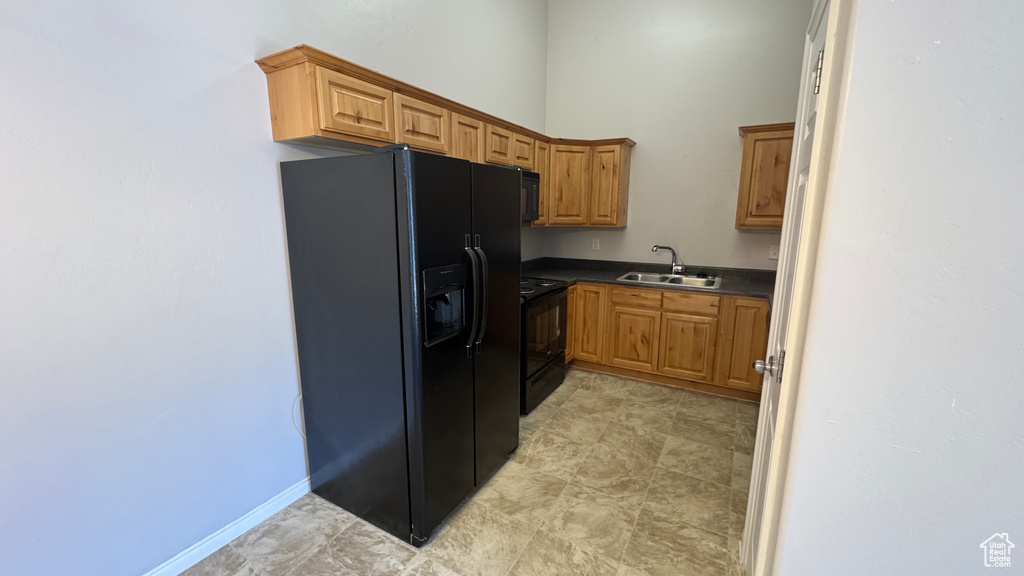 Kitchen with black appliances, dark countertops, a high ceiling, and brown cabinets