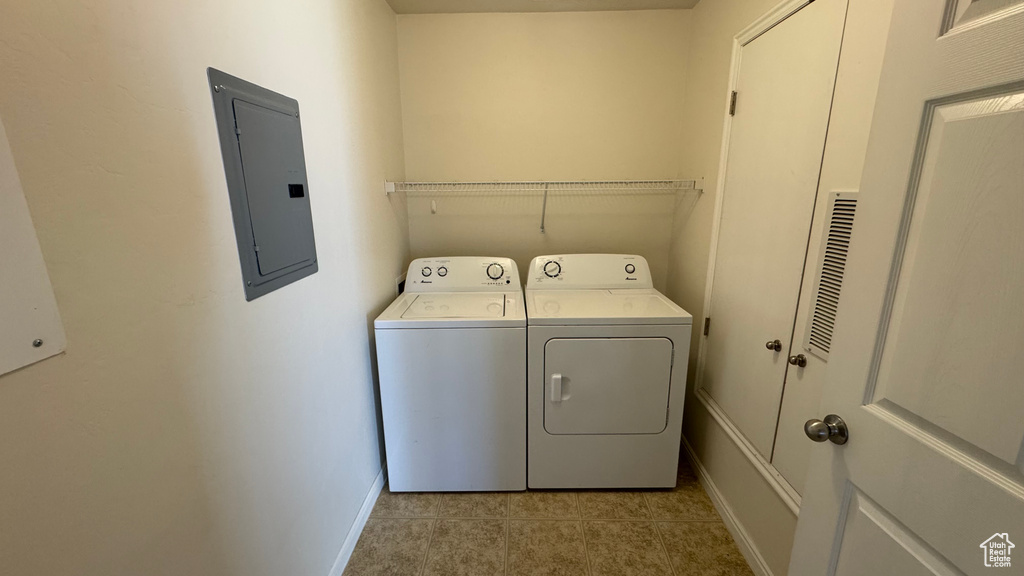 Washroom featuring electric panel, washer and dryer, and light tile patterned floors