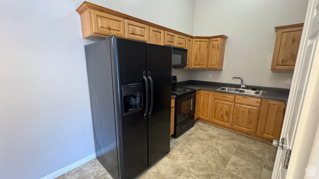 Kitchen with black appliances, dark countertops, and brown cabinetry