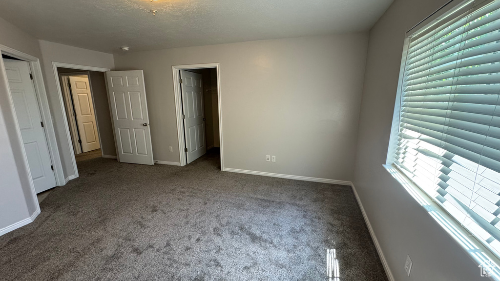 Unfurnished bedroom featuring multiple windows, carpet, and a textured ceiling