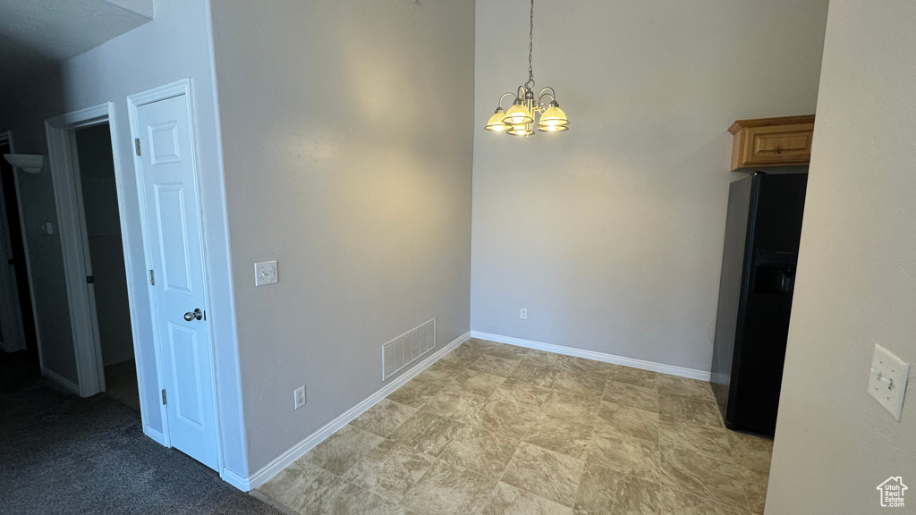 Unfurnished dining area featuring a chandelier and baseboards