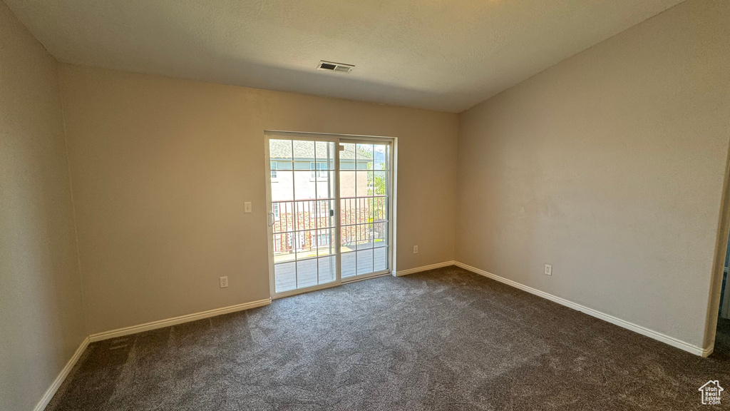 Empty room featuring dark colored carpet and baseboards