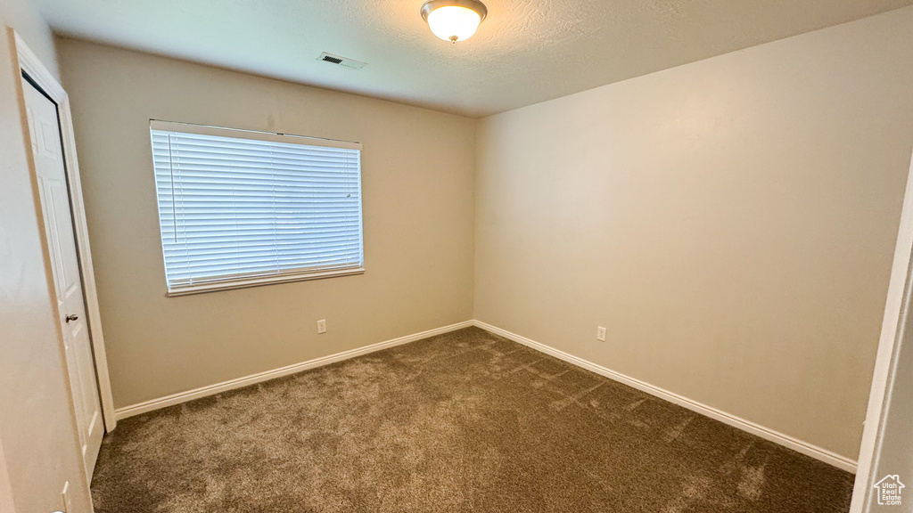 Unfurnished room featuring dark carpet and baseboards