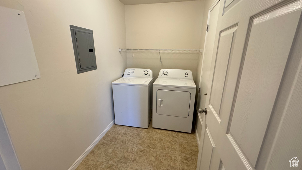 Laundry area featuring electric panel, separate washer and dryer, baseboards, and light tile patterned floors
