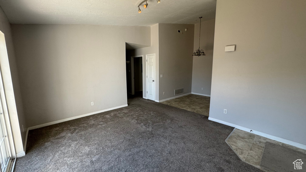 Spare room with dark colored carpet and lofted ceiling
