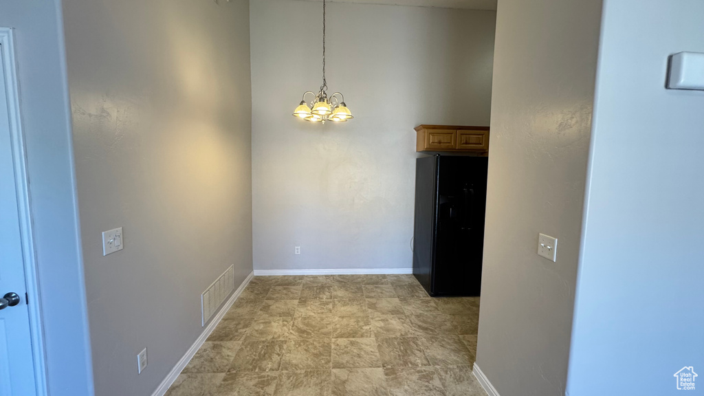 Unfurnished dining area featuring a chandelier and baseboards