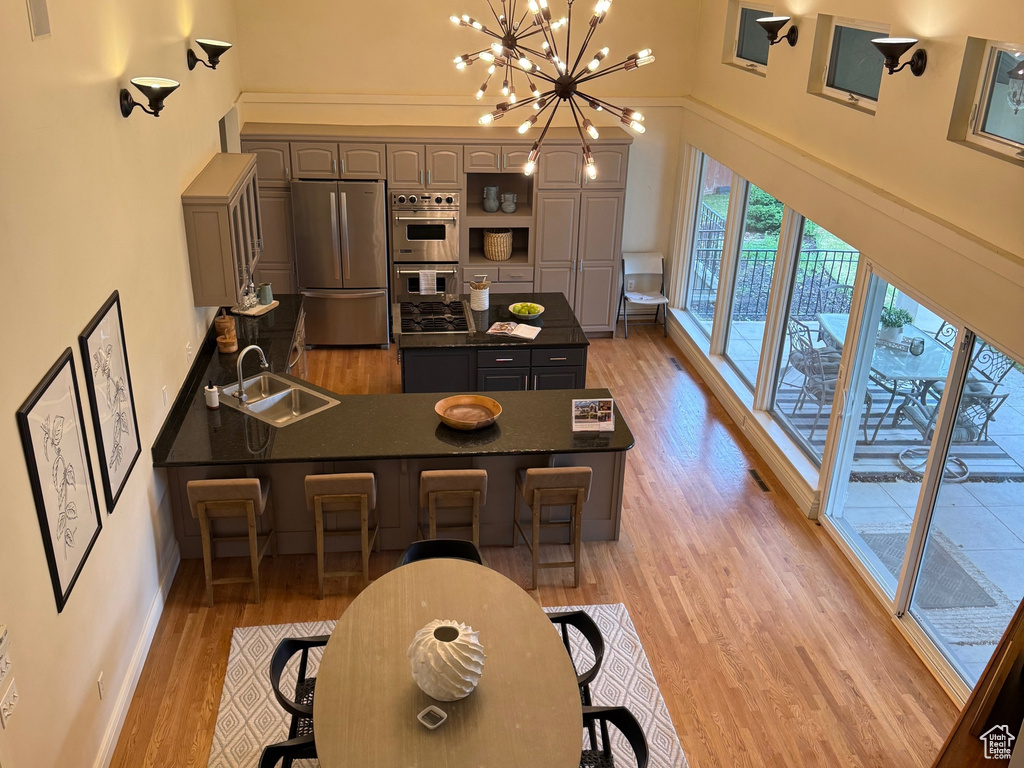 Dining space with high vaulted ceiling, light wood-type flooring, a chandelier, arched walkways, and baseboards
