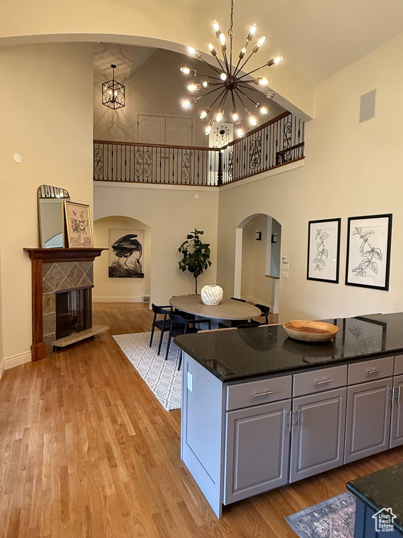 Kitchen with an inviting chandelier, a high ceiling, arched walkways, and light wood-type flooring