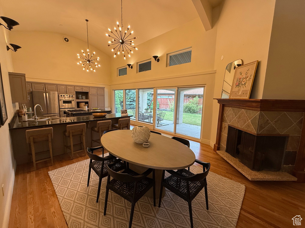 Dining room featuring a tiled fireplace, a chandelier, wood finished floors, and high vaulted ceiling