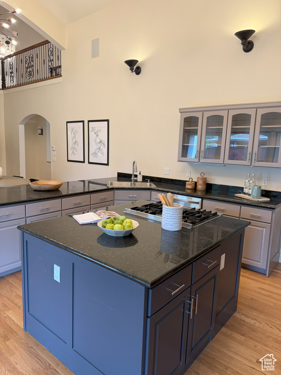 Kitchen featuring arched walkways, light wood-style floors, a center island, and stainless steel gas stovetop