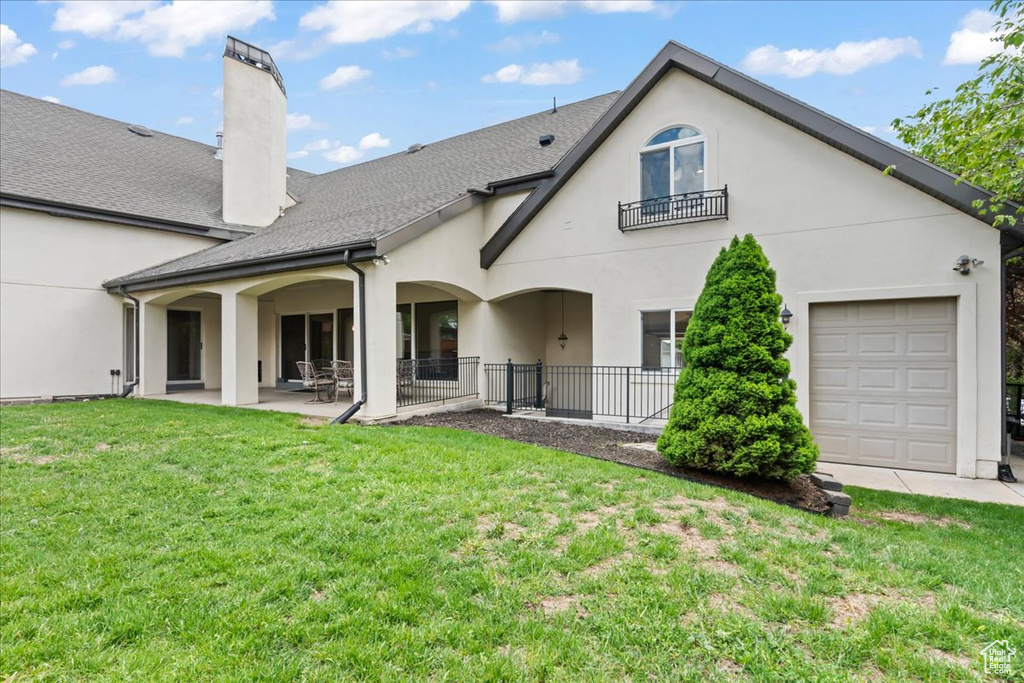 Rear view of property with a yard, a patio, a chimney, stucco siding, and a shingled roof
