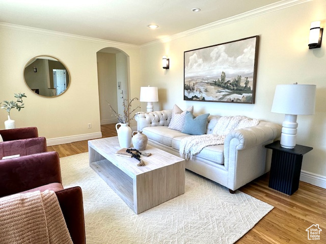 Living area with arched walkways, recessed lighting, baseboards, light wood-type flooring, and ornamental molding