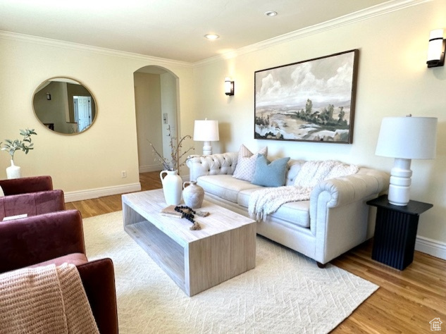 Living area with arched walkways, recessed lighting, baseboards, light wood-type flooring, and ornamental molding