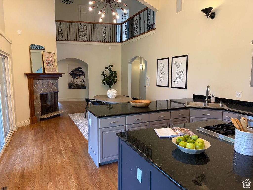 Kitchen featuring a sink, arched walkways, a high ceiling, light wood-type flooring, and a chandelier