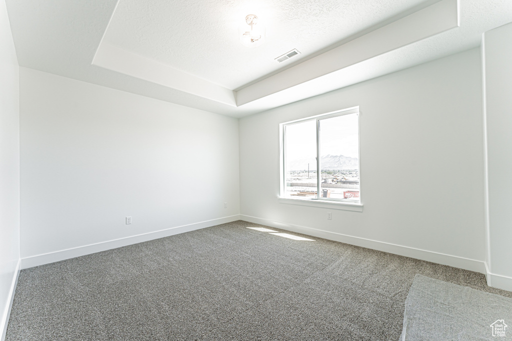 Carpeted empty room with baseboards and a tray ceiling