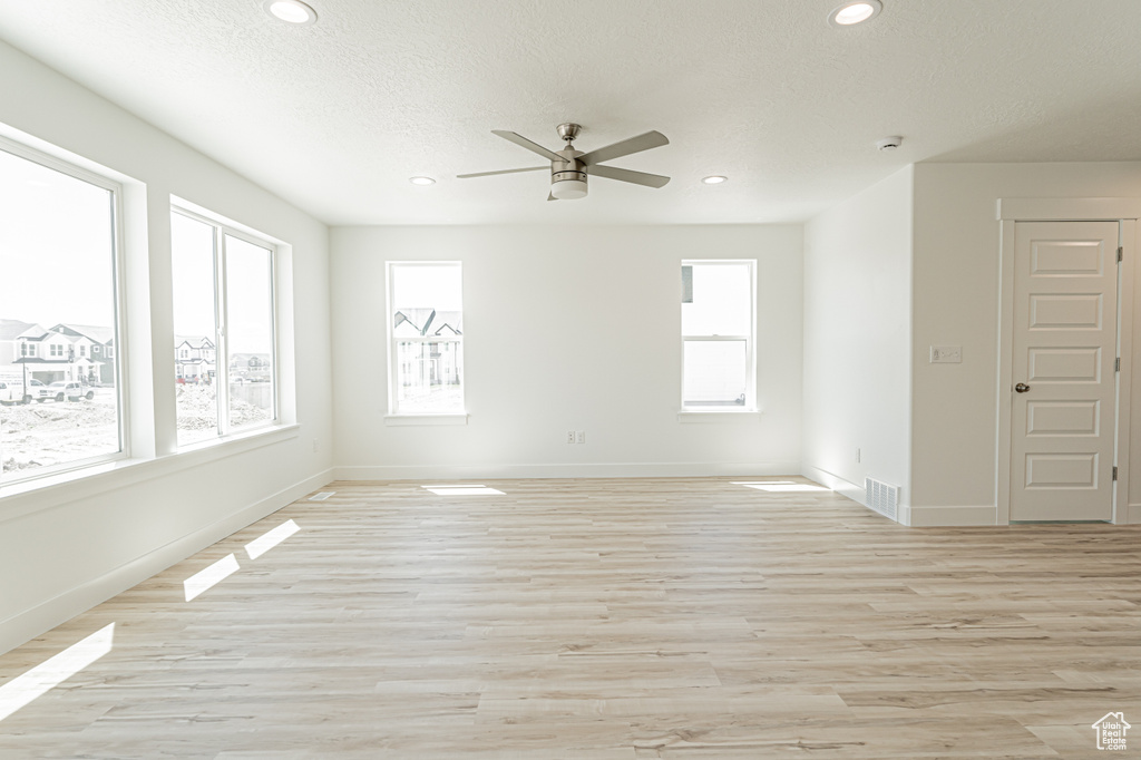 Empty room with plenty of natural light, ceiling fan, light wood finished floors, recessed lighting, and baseboards