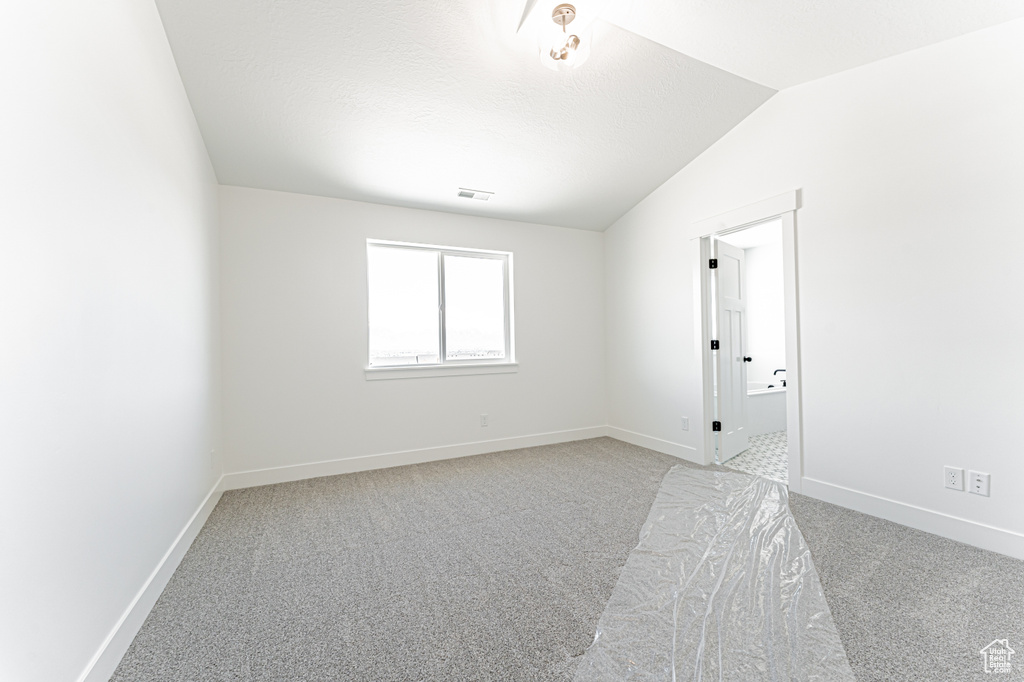 Spare room with carpet floors, baseboards, and lofted ceiling