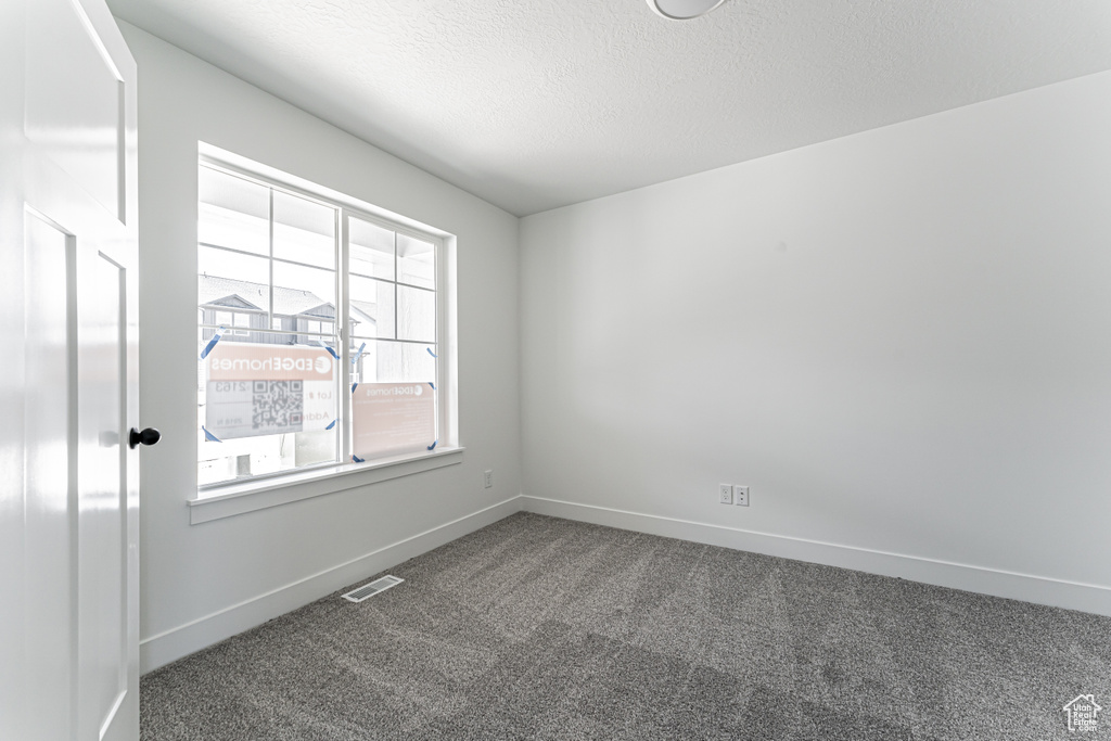 Unfurnished room with carpet floors, baseboards, and a textured ceiling