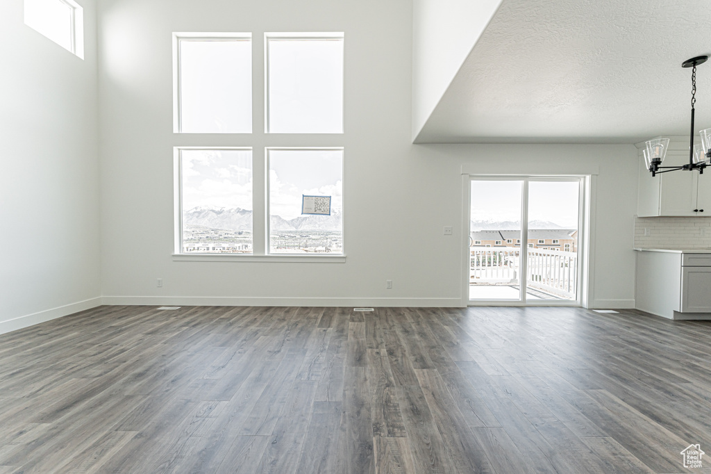 Unfurnished living room with a chandelier, wood finished floors, and baseboards