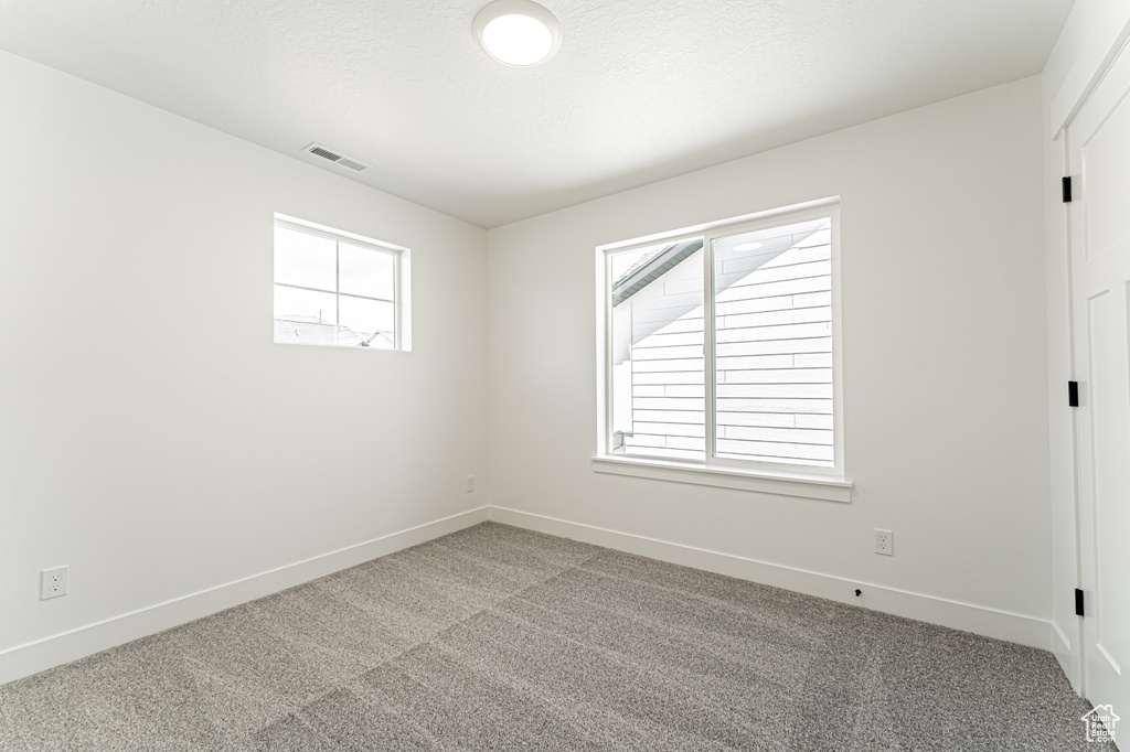 Empty room with light colored carpet and baseboards
