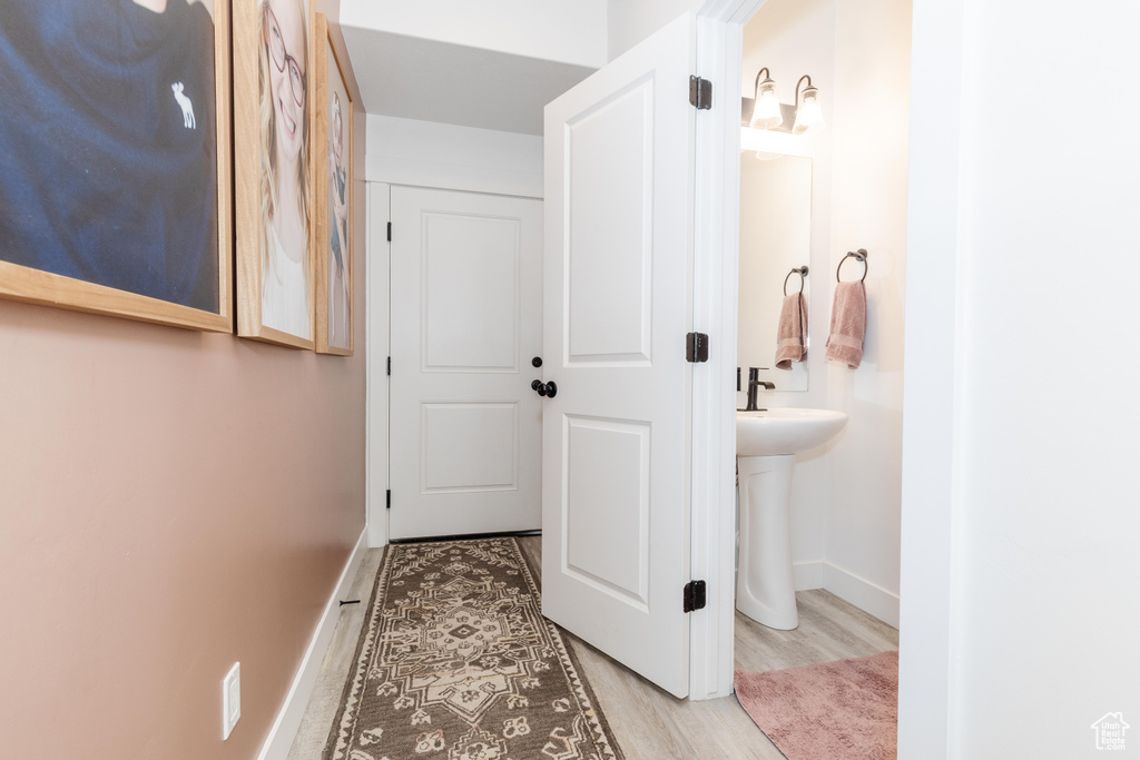 Hallway with a sink, baseboards, and wood finished floors