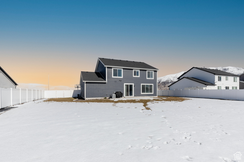 Snow covered back of property with a fenced backyard