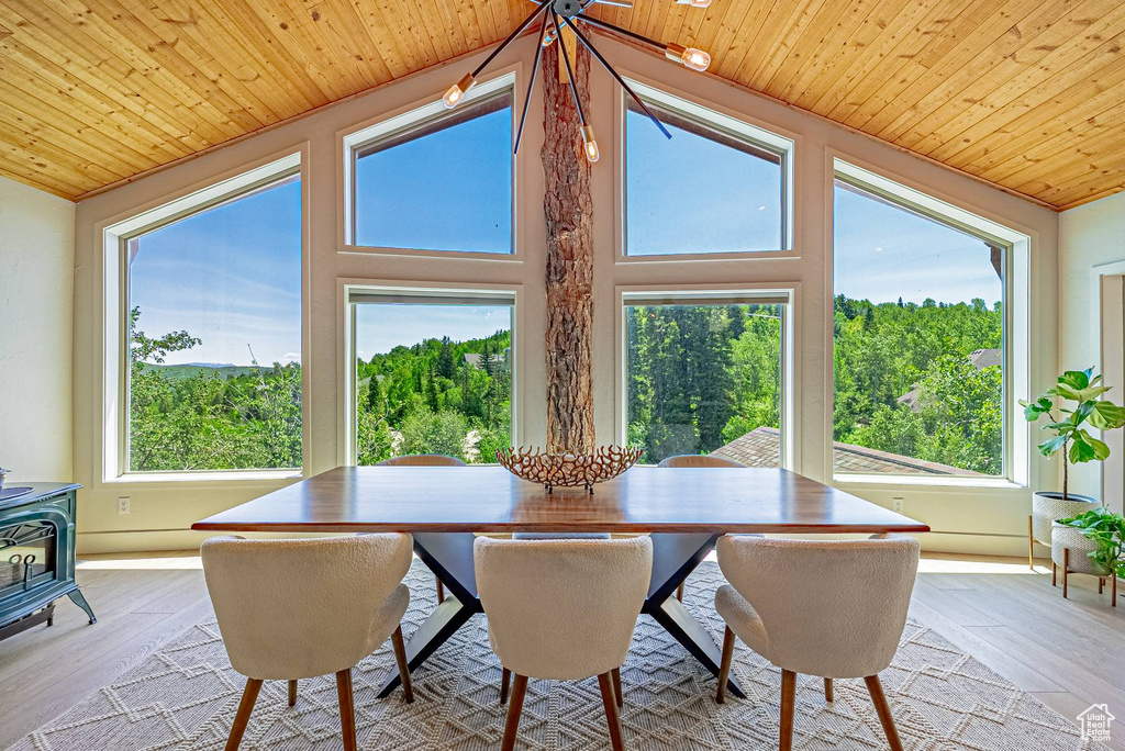 Dining space with wood ceiling, a wood stove, vaulted ceiling, and light wood-style flooring