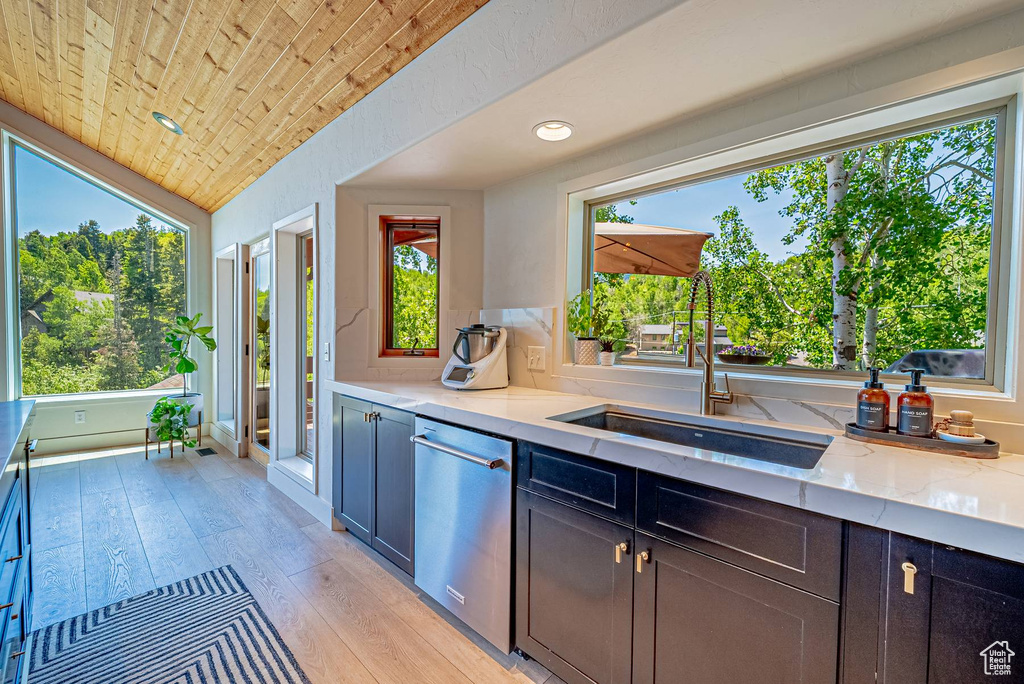 Kitchen with stainless steel dishwasher, a sink, wooden ceiling, light wood-style flooring, and light stone counters