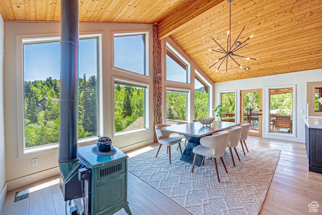 Sunroom / solarium with plenty of natural light, a wood stove, and a chandelier