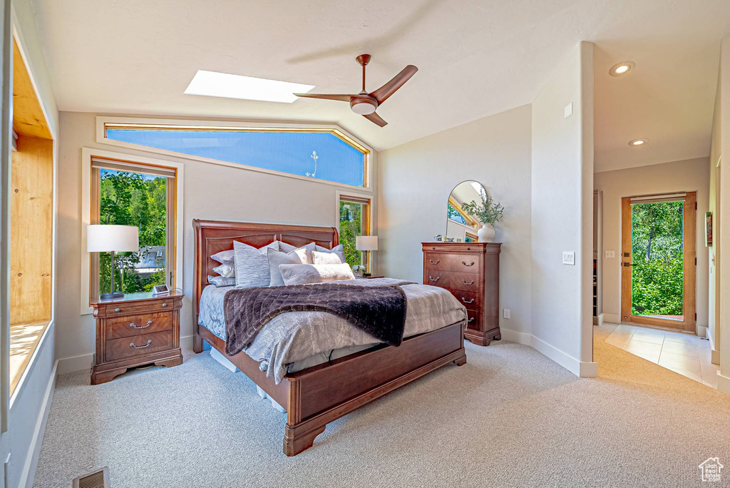 Bedroom featuring a skylight, carpet flooring, vaulted ceiling, a ceiling fan, and baseboards