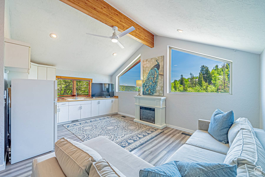 Living room featuring a ceiling fan, light wood-type flooring, recessed lighting, a glass covered fireplace, and baseboards