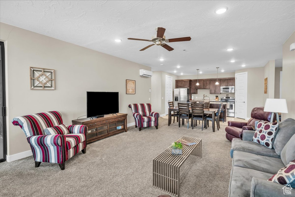 Living area with light carpet, a wall unit AC, baseboards, and recessed lighting