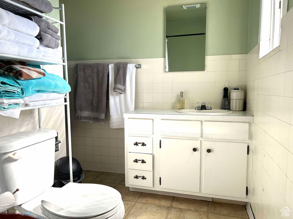 Bathroom featuring tile patterned flooring, vanity, toilet, and tile walls