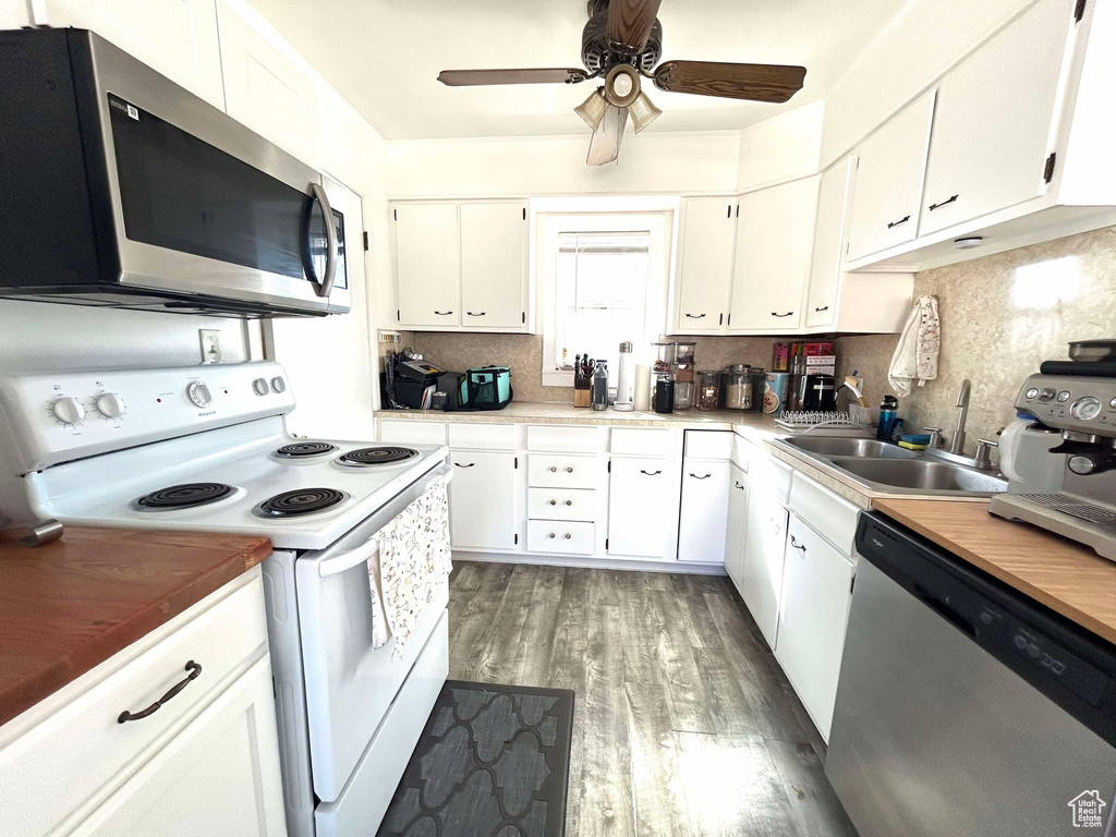 Kitchen with tasteful backsplash, appliances with stainless steel finishes, white cabinetry, ceiling fan, and light wood-type flooring