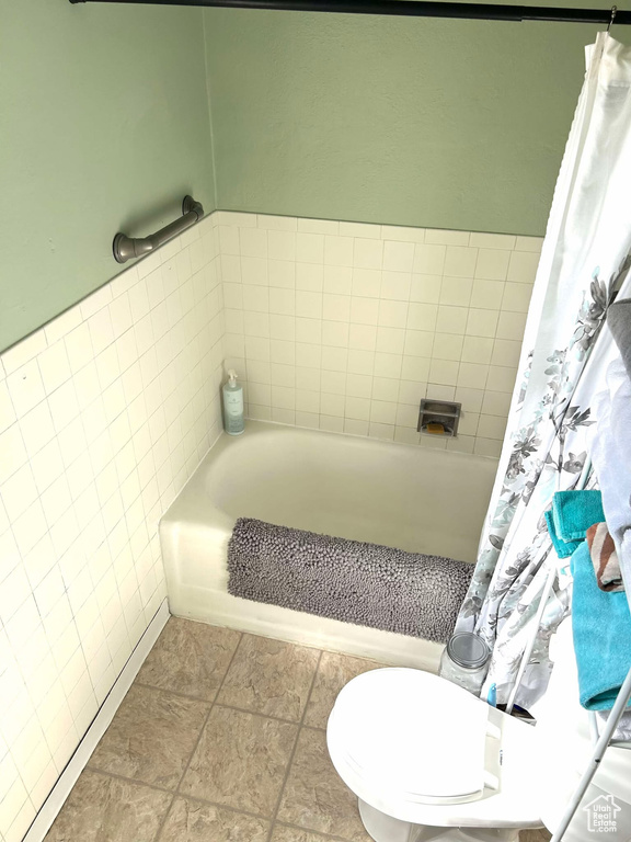 Bathroom with toilet, tile walls, and a tub