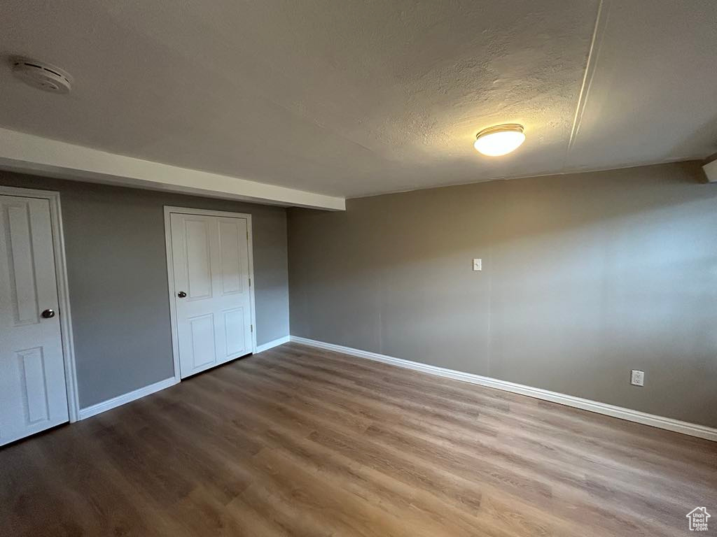 Unfurnished bedroom with baseboards, a textured ceiling, and wood finished floors