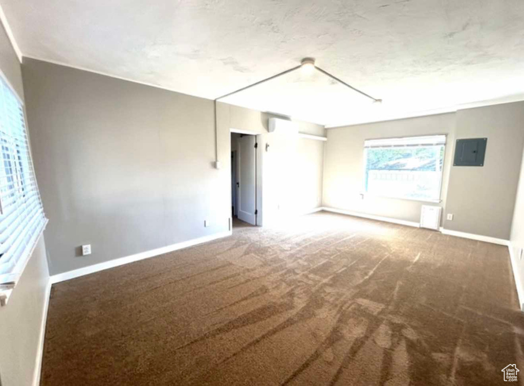 Spare room with dark colored carpet, electric panel, and baseboards