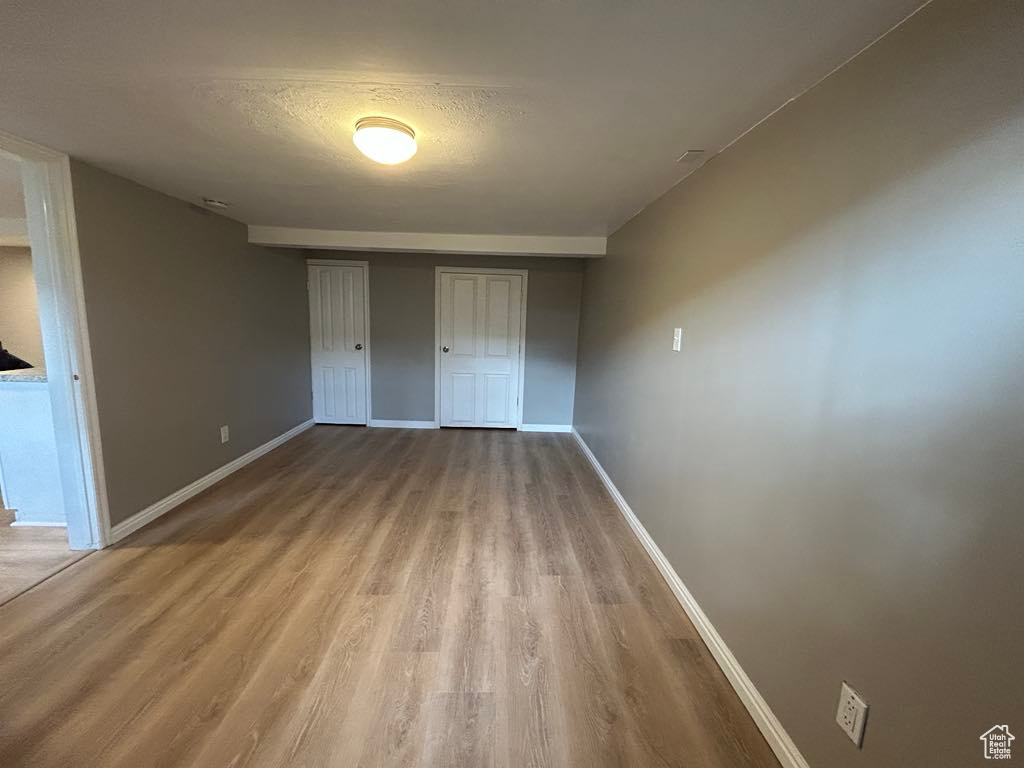 Unfurnished bedroom featuring a closet, a textured ceiling, baseboards, and wood finished floors